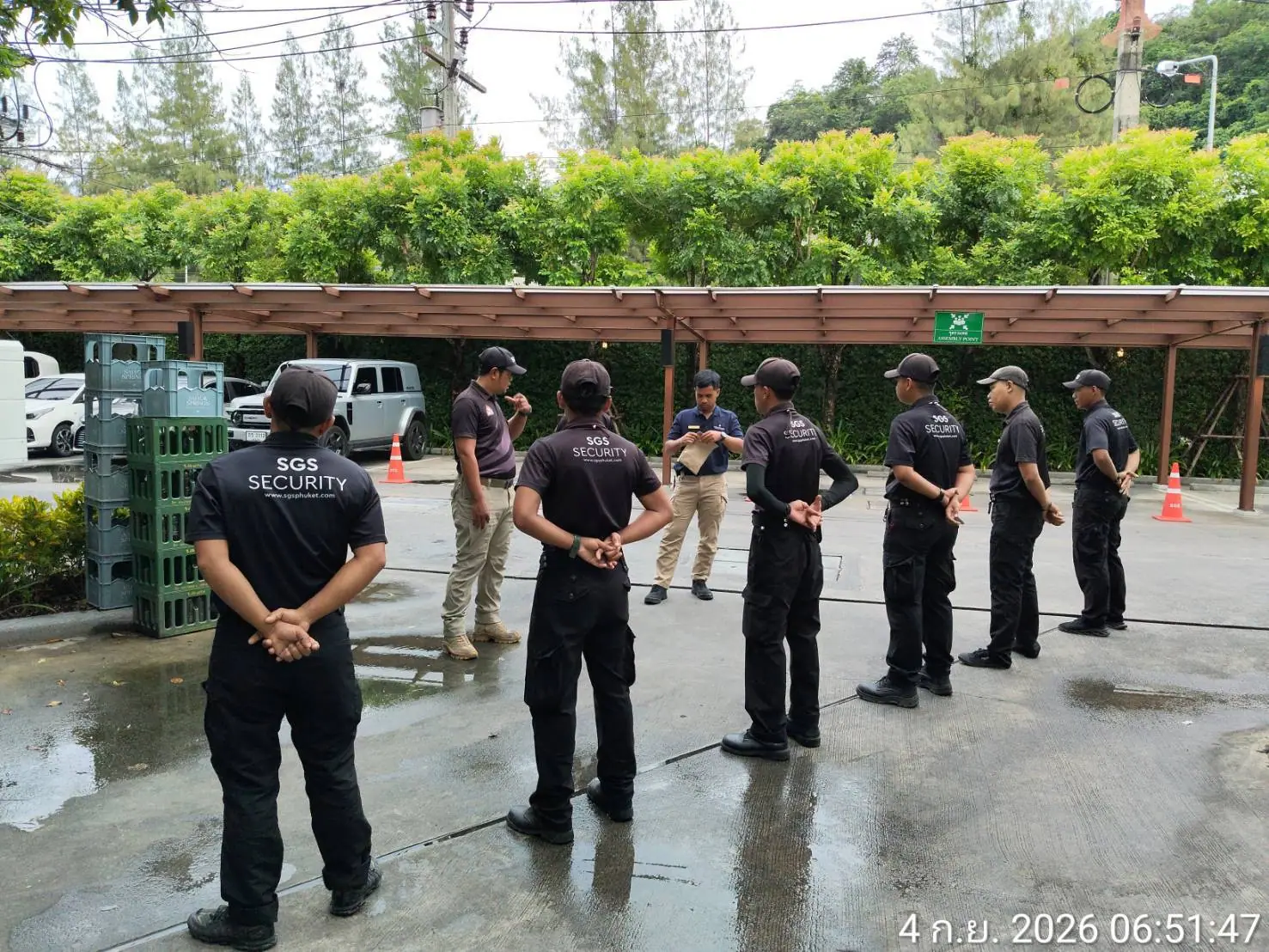 SGS supervisor briefing a line of security officers beside the assembly point sign on the back-of-house apron at InterContinental Phuket Resort, Kamala