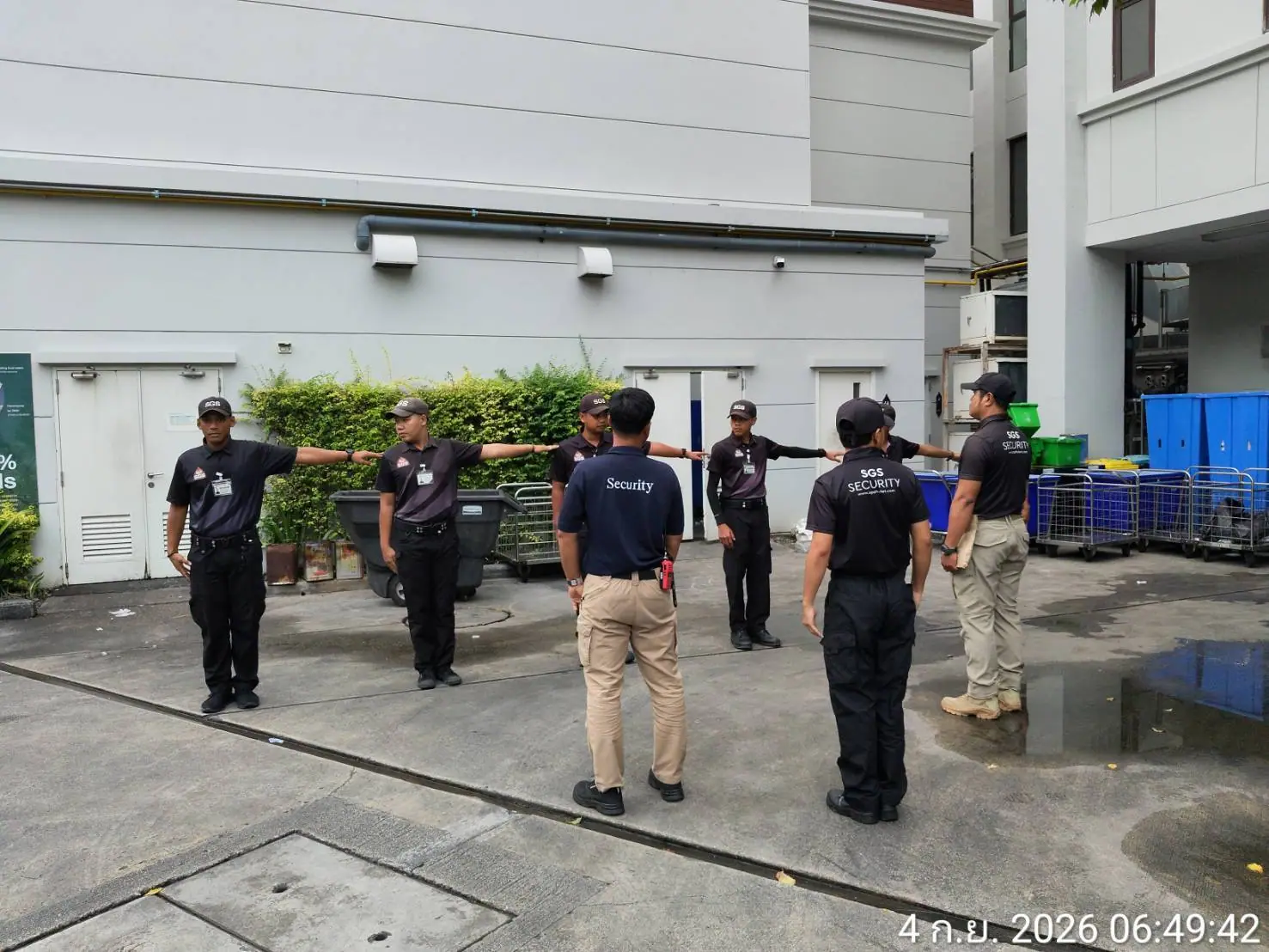 Six SGS security officers dressing ranks with arms extended while a supervisor checks the spacing on the loading apron at InterContinental Phuket Resort, Kamala