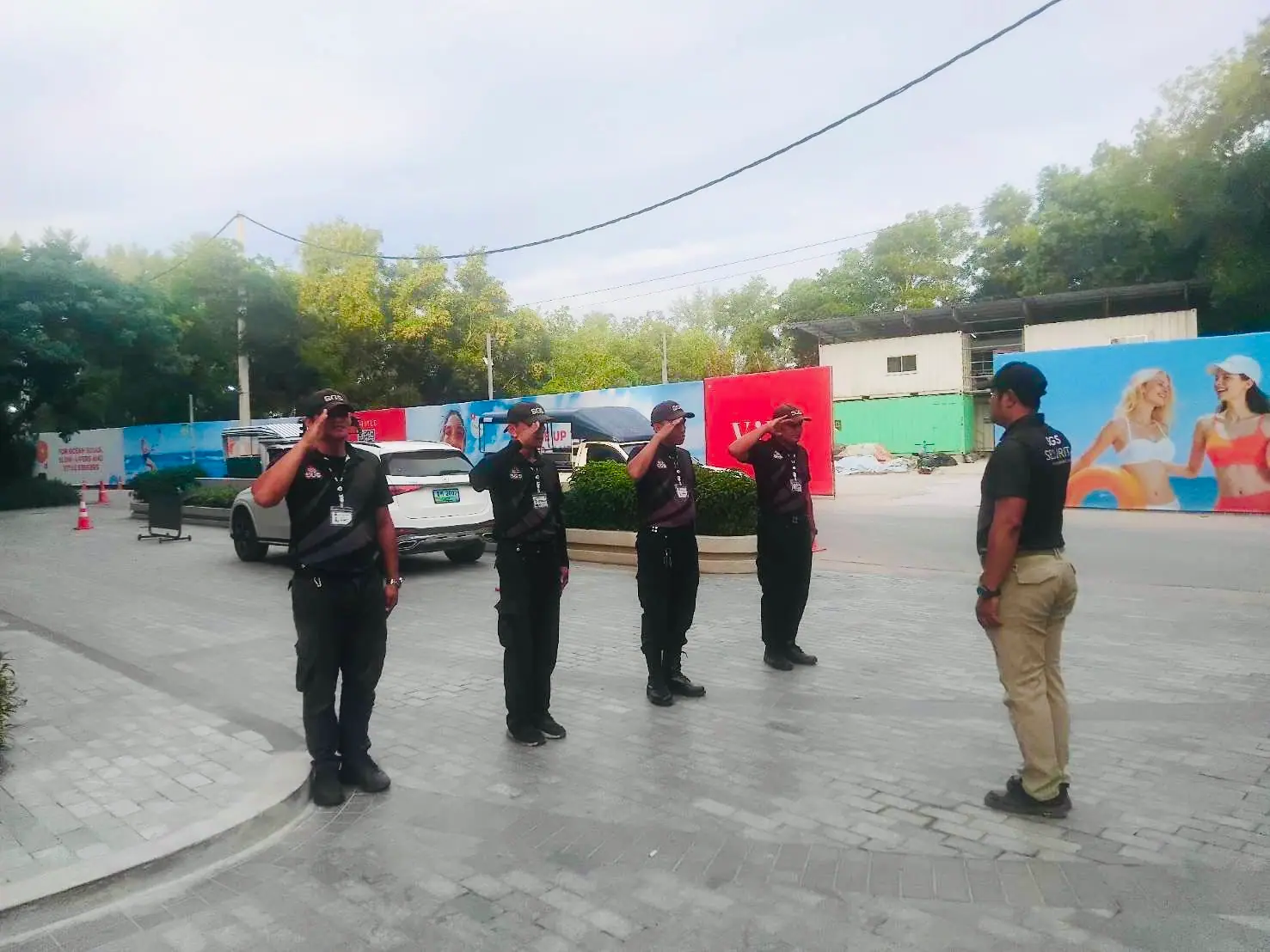 Four SGS security officers saluting a supervisor in front of the site hoarding at The Title Legendary, Bangtao, Phuket