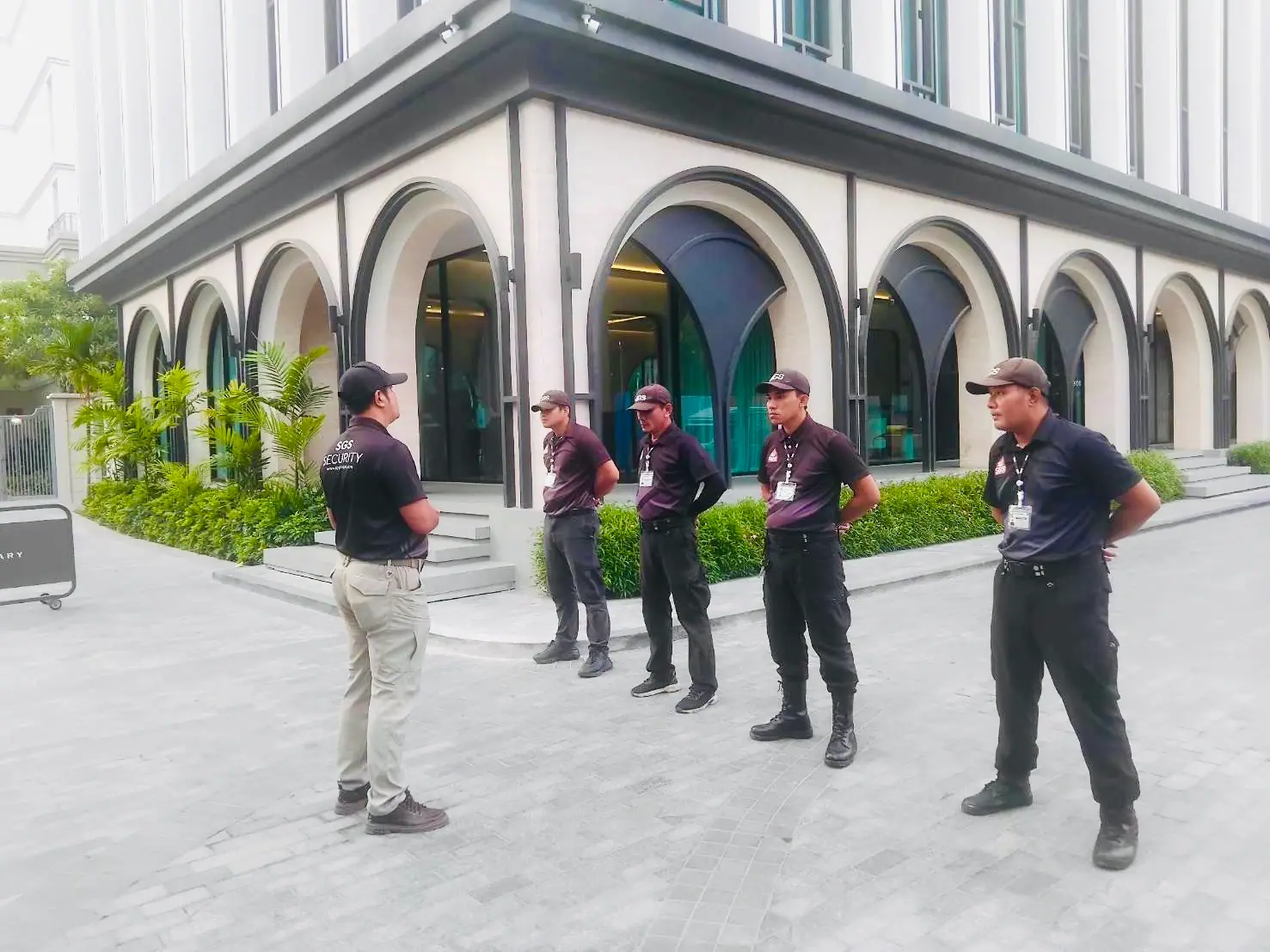 SGS supervisor briefing four security officers in front of the arched facade of The Title Legendary, Bangtao